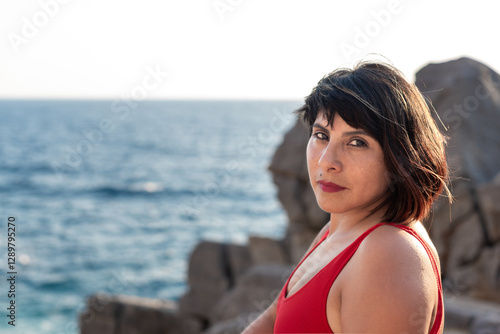 candid portrait of beautiful woman in her 40s in swimsuit with blurred background of Mediterranean sea. Portrait with Polaroid analogic film vibes and style.