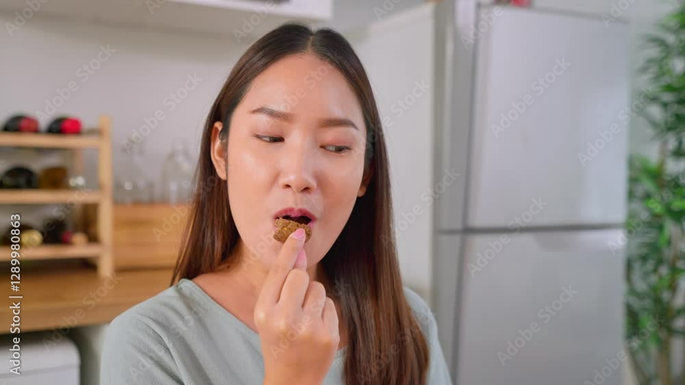 Asian attractive woman eating delicious cookies in kitchen at home. Asian attractive woman eating delicious cookies in kitchen at home.