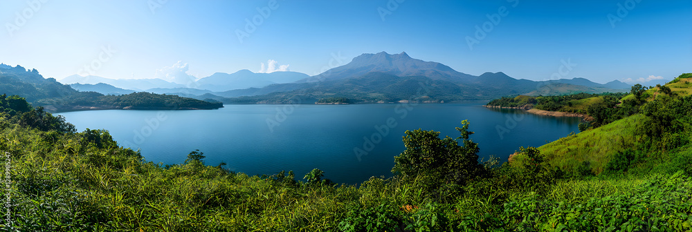 Serenity of a Sprawling Reservoir Encircled by Lush Greenery and Majestic Mountains Amidst a Clear Sky Serenity of a Sprawling Reservoir Encircled by Lush Greenery and Majestic Mountains Amidst a Clear Sky