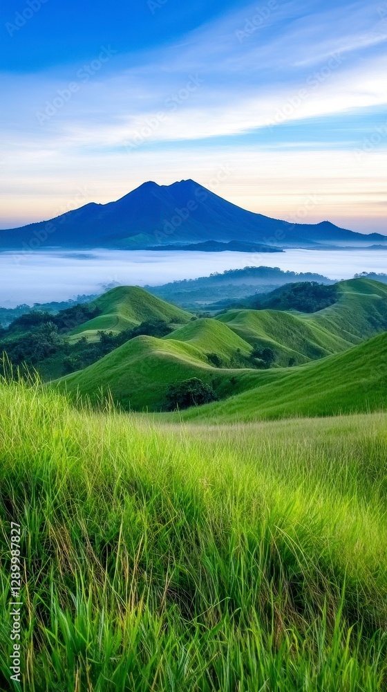 Fototapeta premium Experience the breathtaking beauty of this vibrant landscape, where rolling green hills meet a majestic mountain range shrouded in ethereal mist, creating a serene and captivating panorama that