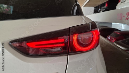 Slika na platnu A close-up view of a modern car's red taillight glowing inside a parking garage,