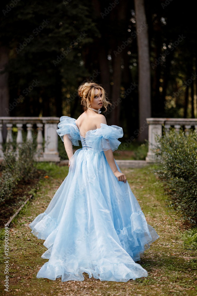 Graceful young woman in elegant light blue dress posing near stone balustrade in picturesque garden. Concept fantasy or historical themes. Graceful young woman in elegant light blue dress posing near stone balustrade in picturesque garden. Concept fantasy or historical themes.