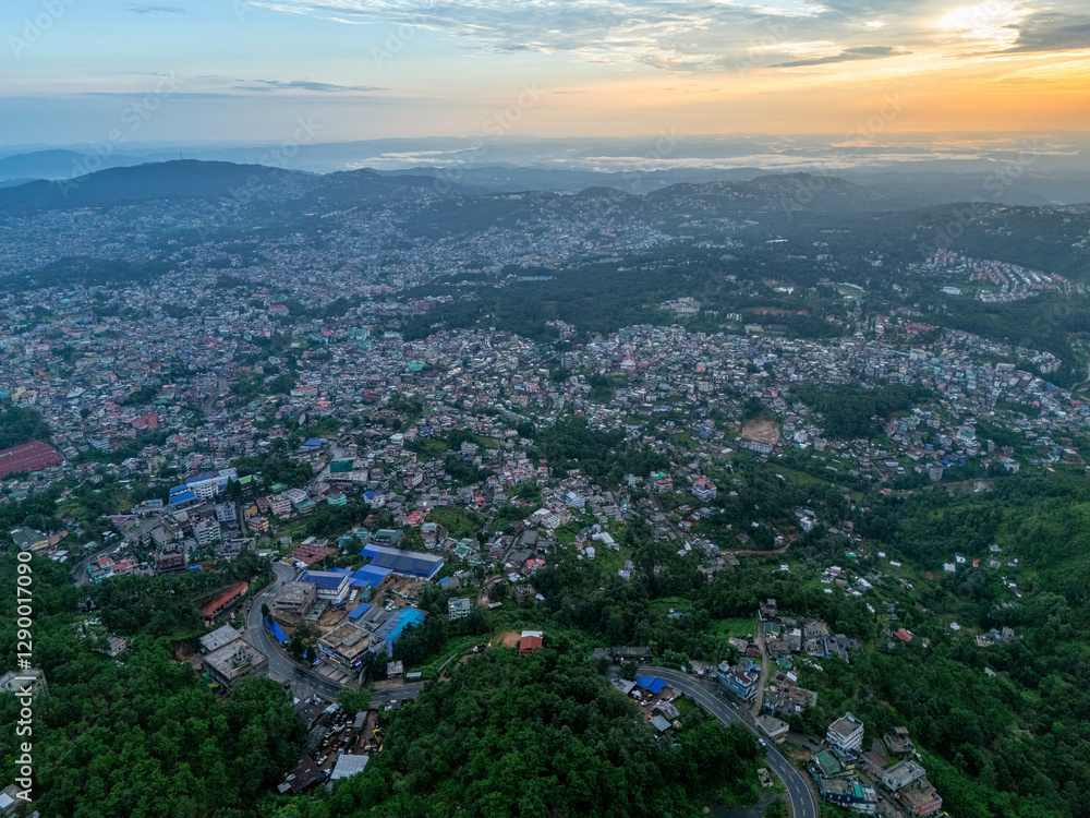 An enchanting aerial shot of Shillong at sunrise, where rolling hills, misty air, and a tranquil cityscape create a picturesque morning scene. An enchanting aerial shot of Shillong at sunrise, where rolling hills, misty air, and a tranquil cityscape create a picturesque morning scene.