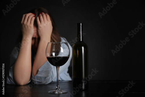 Alcohol addiction. Miserable woman with wine at table in dark. Space for text