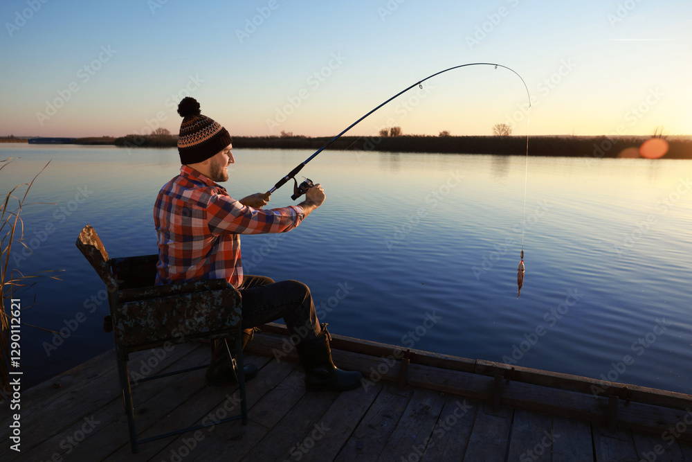 Fisherman catching fish with rod at riverside Fisherman catching fish with rod at riverside