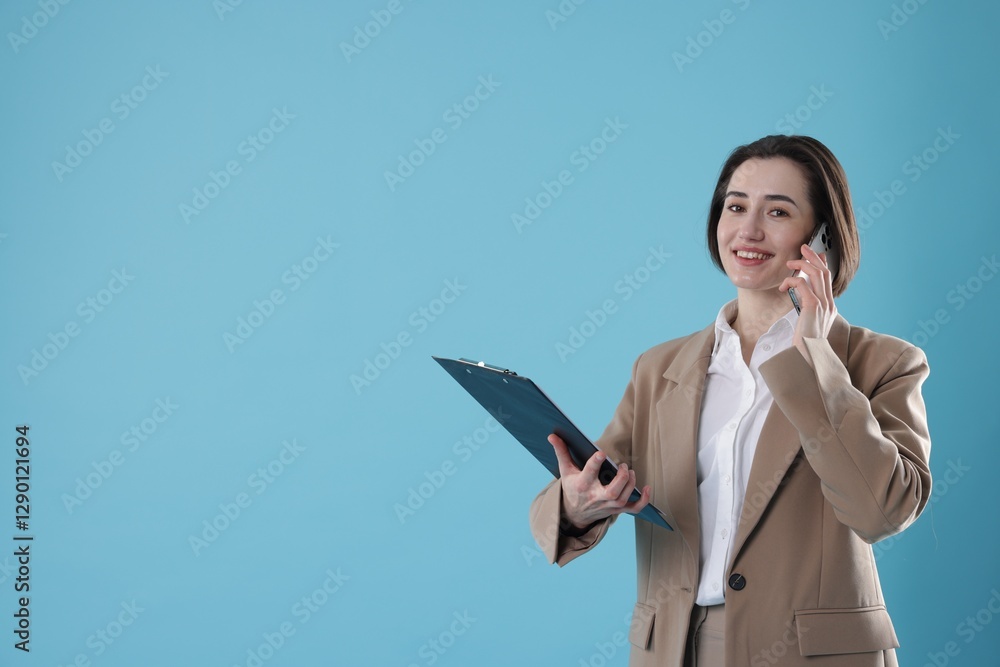 Smiling secretary with clipboard talking on smartphone against light blue background. Space for text Smiling secretary with clipboard talking on smartphone against light blue background. Space for text