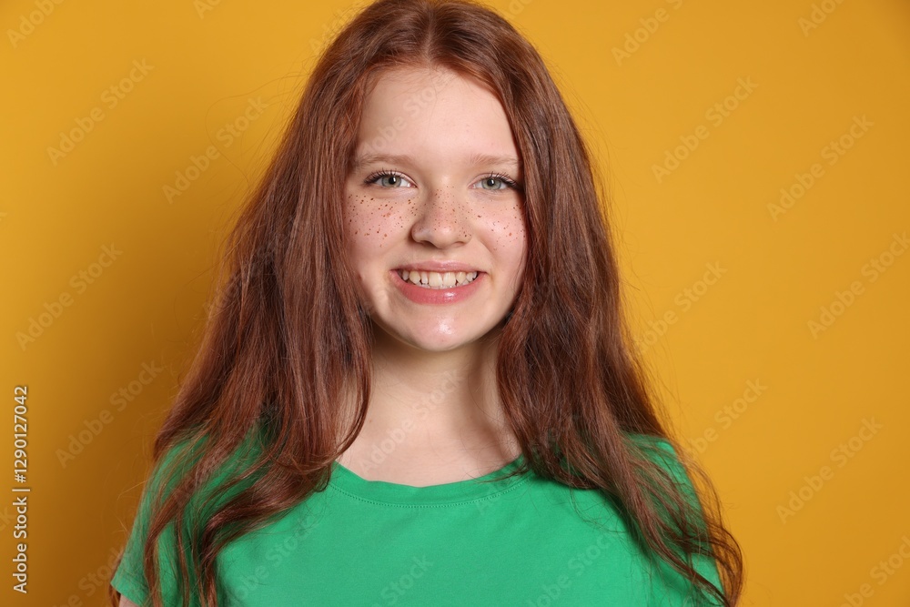 Fototapeta premium Beautiful teenage girl with freckles on orange background