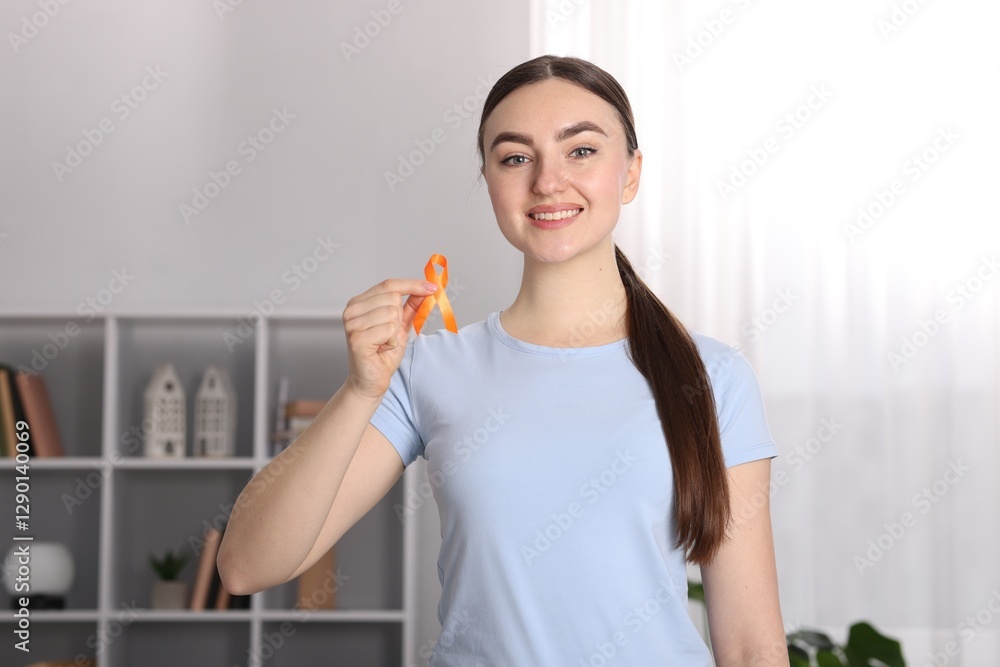 Multiple Sclerosis awareness. Happy young woman holding orange ribbon indoors Multiple Sclerosis awareness. Happy young woman holding orange ribbon indoors