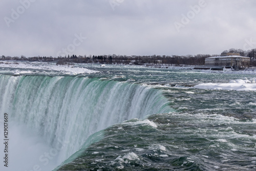 On the edge of Niagara Falls. Turquoise water falls to the bottom.
