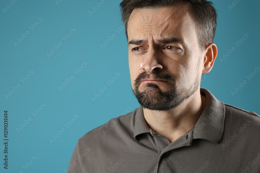 Obraz premium Sad man crying on light blue background, space for text
