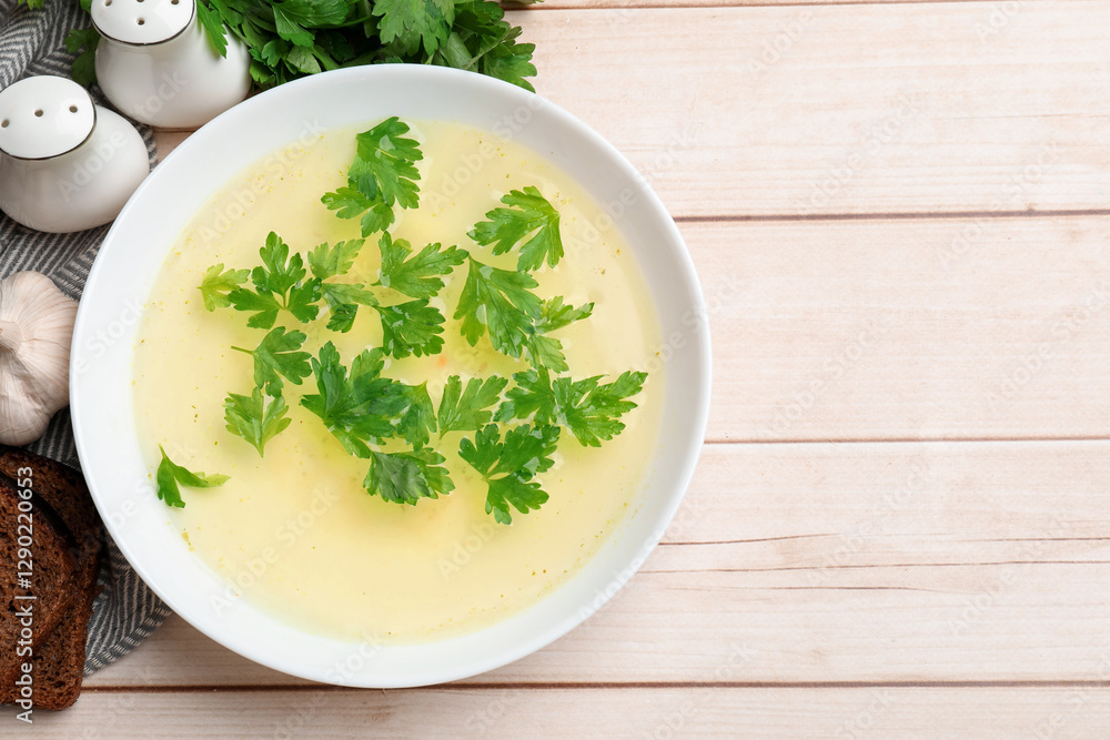Tasty chicken bouillon in bowl with bread and ingredients on wooden table, flat lay. Space for text Tasty chicken bouillon in bowl with bread and ingredients on wooden table, flat lay. Space for text