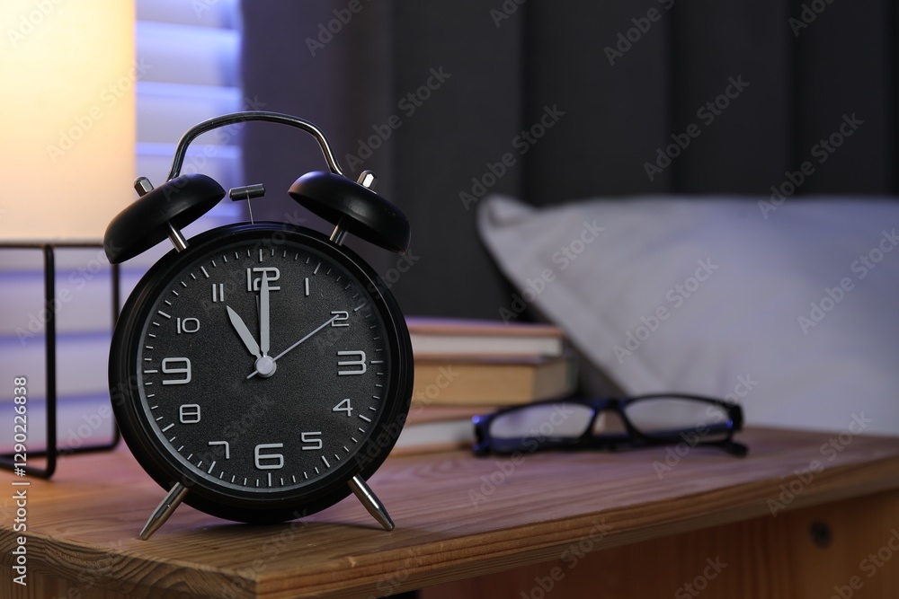 Alarm clock, books and glasses on nightstand near bed. Space for text Alarm clock, books and glasses on nightstand near bed. Space for text