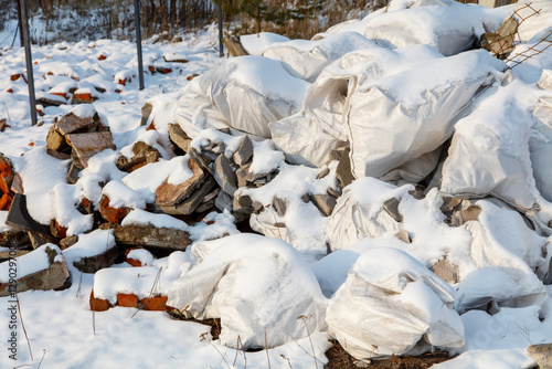 A pile of white plastic bags and rocks covered in snow photo