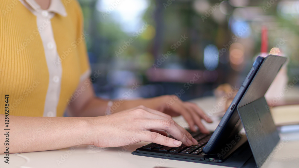 Fototapeta premium Young Asian woman studying with a tablet in a modern university cafe