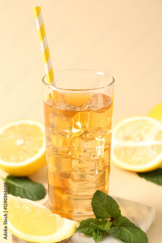 Refreshing iced tea with drinking straw in glass, mint and lemon on beige background, closeup Refreshing iced tea with drinking straw in glass, mint and lemon on beige background, closeup