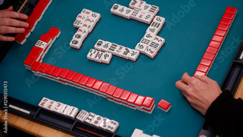 Photos A mahjong table with an active game and the hands of a participant in the game
