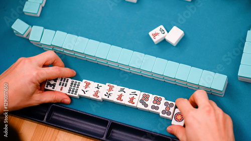 Photos A mahjong table with an active game and the hands of a participant in the game