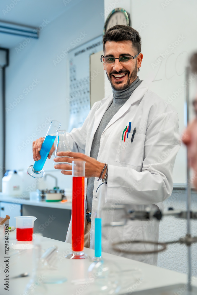 Smiling scientist pouring blue chemical liquid in laboratory glassware Smiling scientist pouring blue chemical liquid in laboratory glassware