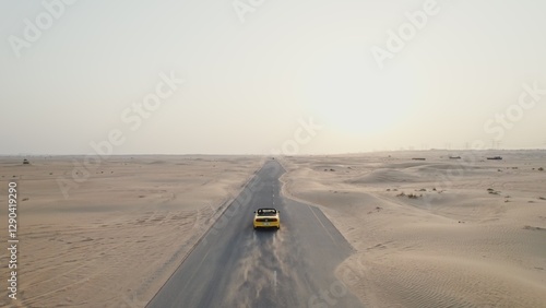 Photography Rear view of a yellow car driving along the road among the desert sands on a sunny day