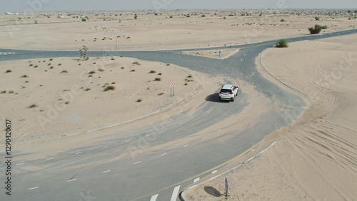Photography The car is driving along the ring road among the sand dunes in the desert