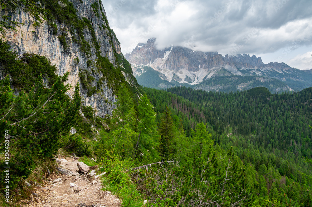 Breathtaking view of forests, mountains, and valleys in the Italian Dolomites (Dolomiti, Dolomiten). Captured from a scenic trail along a rocky ledge. Stunning alpine nature