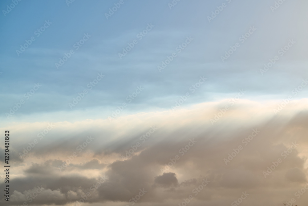 Obraz premium Sunbeams filtering through clouds in blue sky