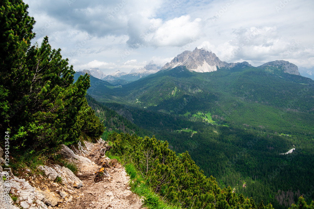 Breathtaking view of forests, mountains, and valleys in the Italian Dolomites (Dolomiti, Dolomiten). Captured from a scenic trail along a rocky ledge. Stunning alpine nature