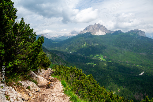 Breathtaking view of forests, mountains, and valleys in the Italian Dolomites (Dolomiti, Dolomiten). Captured from a scenic trail along a rocky ledge. Stunning alpine nature
