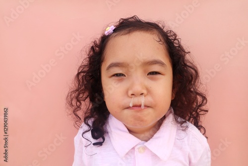 Asian female toddler having a bad cold with snot coming out of her nose, close up view.