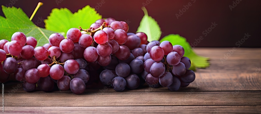 Fresh clusters of red and purple grapes arranged on a rustic wooden table with green leaves in the background, softly lit for a warm ambiance. Fresh clusters of red and purple grapes arranged on a rustic wooden table with green leaves in the background, softly lit for a warm ambiance.