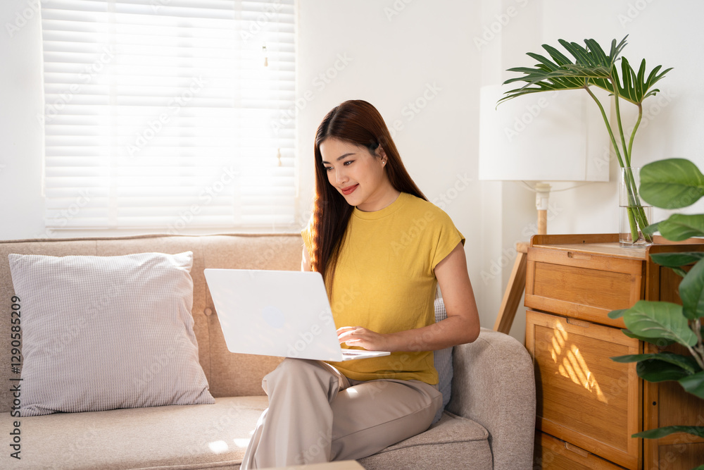 Happy casual beautiful woman using laptop at home. Woman working on laptop computer, sitting on sofa, copy space. Happy casual beautiful woman using laptop at home. Woman working on laptop computer, sitting on sofa, copy space.