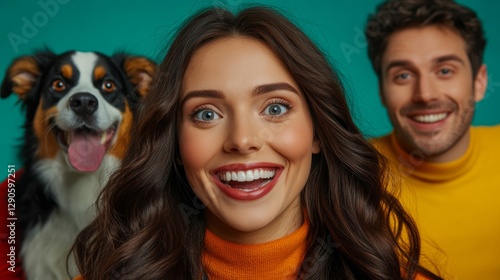 Woman and a man are smiling and posing with a dog. The woman is wearing a yellow sweater and the man is wearing a red shirt. The dog is wagging its tail and looking at the camera