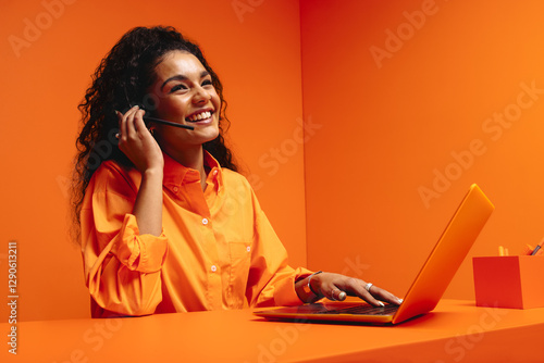 Smiling woman customer support agent in vibrant orange monochromatic office setting