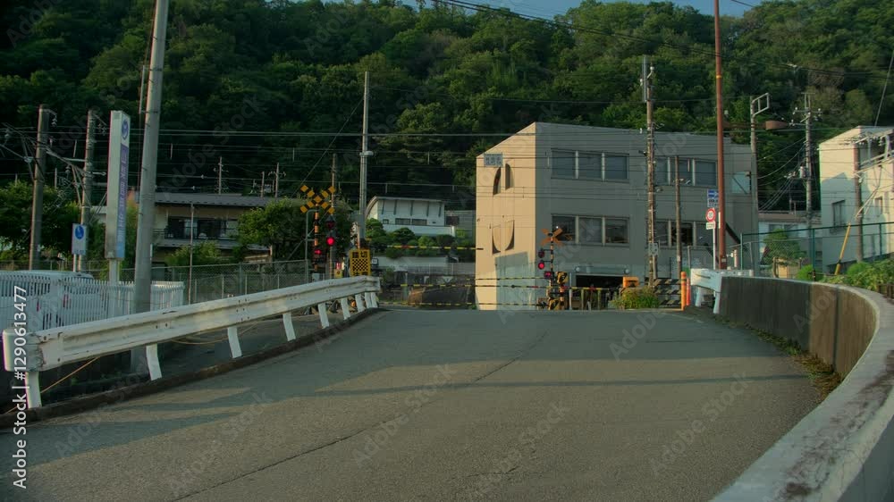 Railroad Crossing in Rural Japan at Sunset – A scenic view of a railway crossing in a Japanese village with red signal lights flashing as the barrier lowers, set against mountains and forests Railroad Crossing in Rural Japan at Sunset – A scenic view of a railway crossing in a Japanese village with red signal lights flashing as the barrier lowers, set against mountains and forests
