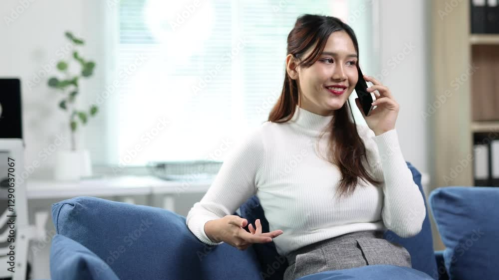 Asian freelancer engages in a phone conversation while working remotely from a stylish home office, modern lifestyle and the comforts of a productive work. Asian freelancer engages in a phone conversation while working remotely from a stylish home office, modern lifestyle and the comforts of a productive work.
