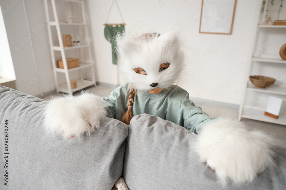 Quadrober girl in cat mask behind sofa at home Quadrober girl in cat mask behind sofa at home