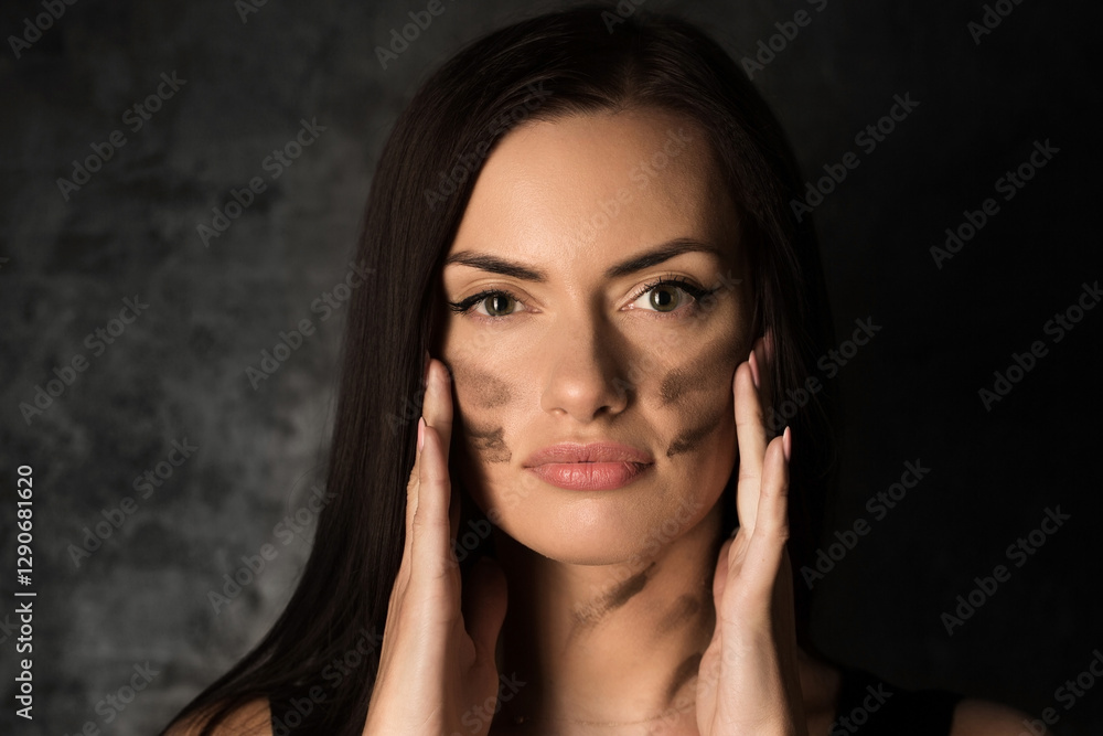 Beautiful woman applying camouflage military makeup