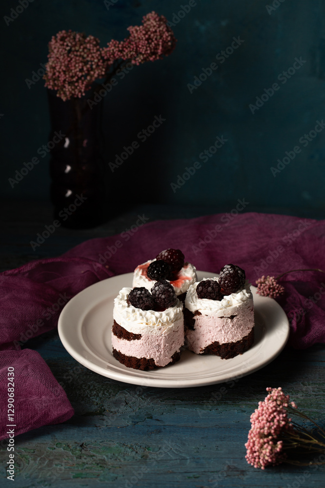 Delicious cream cakes with blackberries on a plate. Still life in a rustic style