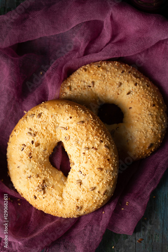 Obraz na płótnie Homemade large bagels with sesame and sunflower seeds on burgundy gauze, top view w salonie