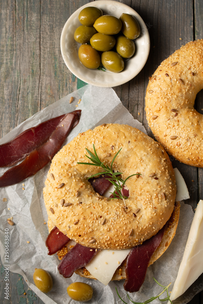 Burger with cheese, basturma, olives and rosemary on a wooden table