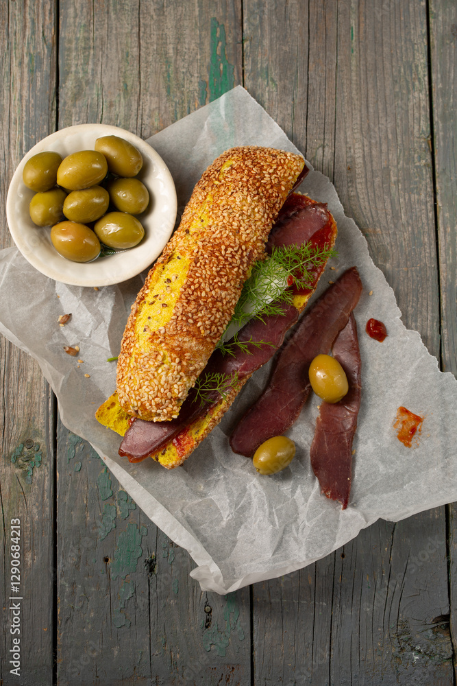 Burger with ciabatta with turmeric, bastrum and olives, top view