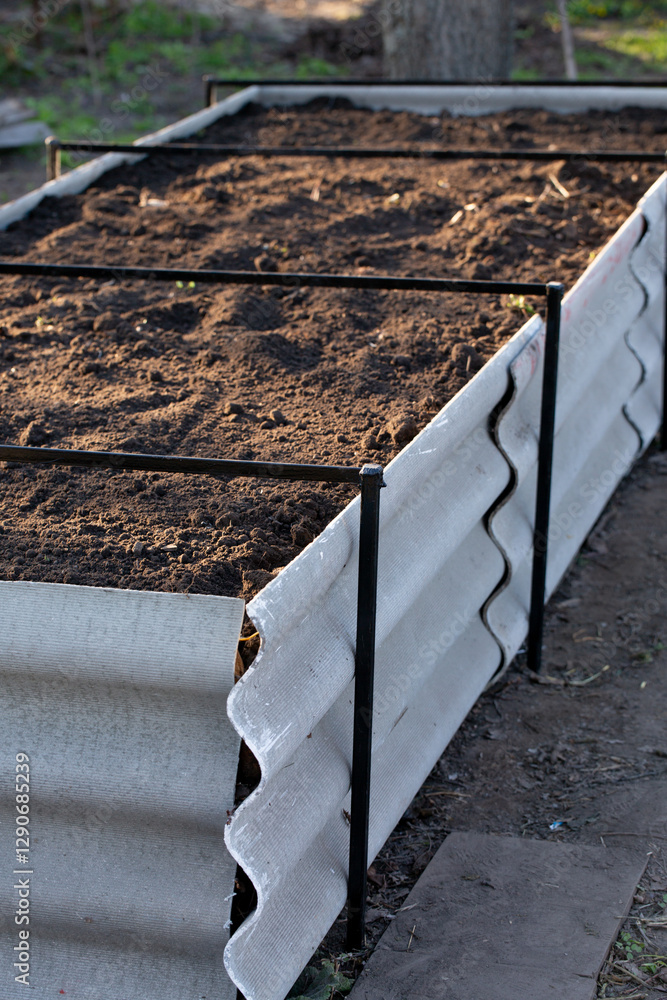 Permaculture raised warm bed made of slate with branches at the base