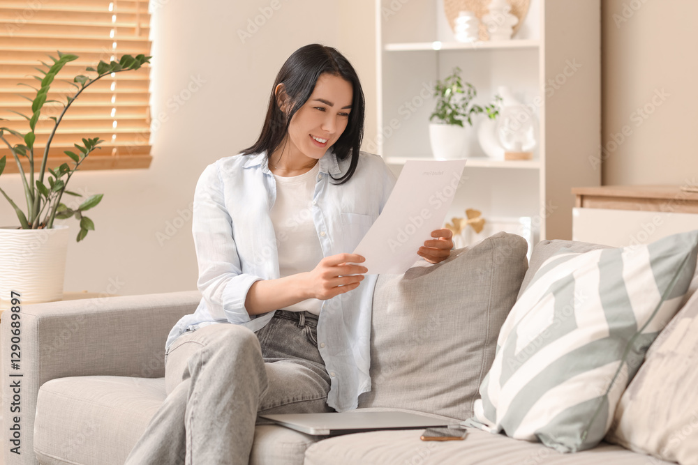 Young woman with refund form sitting on sofa at home Young woman with refund form sitting on sofa at home