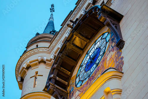 A close-up of the iconic clock tower of the Palace of Culture in Iași, Romania, framed by blooming tulips in the foreground