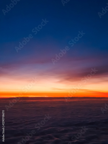 A breathtaking sunrise above the clouds, painting the sky with warm hues of orange, pink, and deep blue