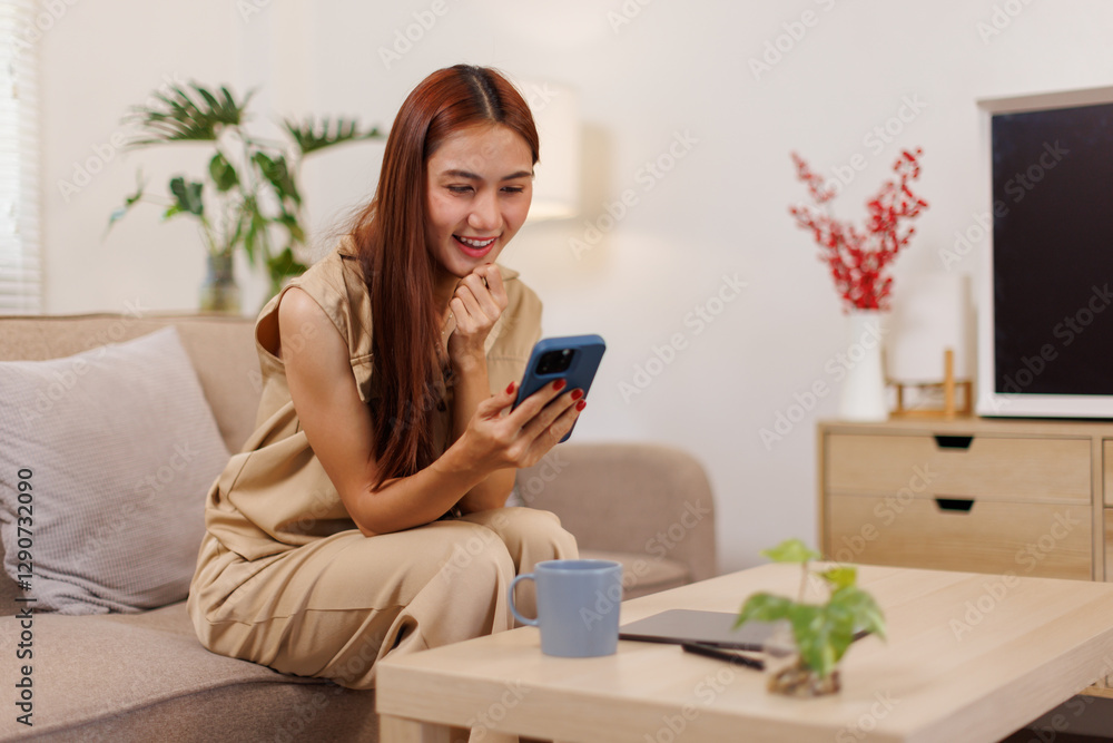 Beautiful confident asian business woman sitting on cozy couch, using funny mobile apps in living room. Woman at Home, Doing Online Shopping, Messaging Friends, Posting on Social Media Beautiful confident asian business woman sitting on cozy couch, using funny mobile apps in living room. Woman at Home, Doing Online Shopping, Messaging Friends, Posting on Social Media