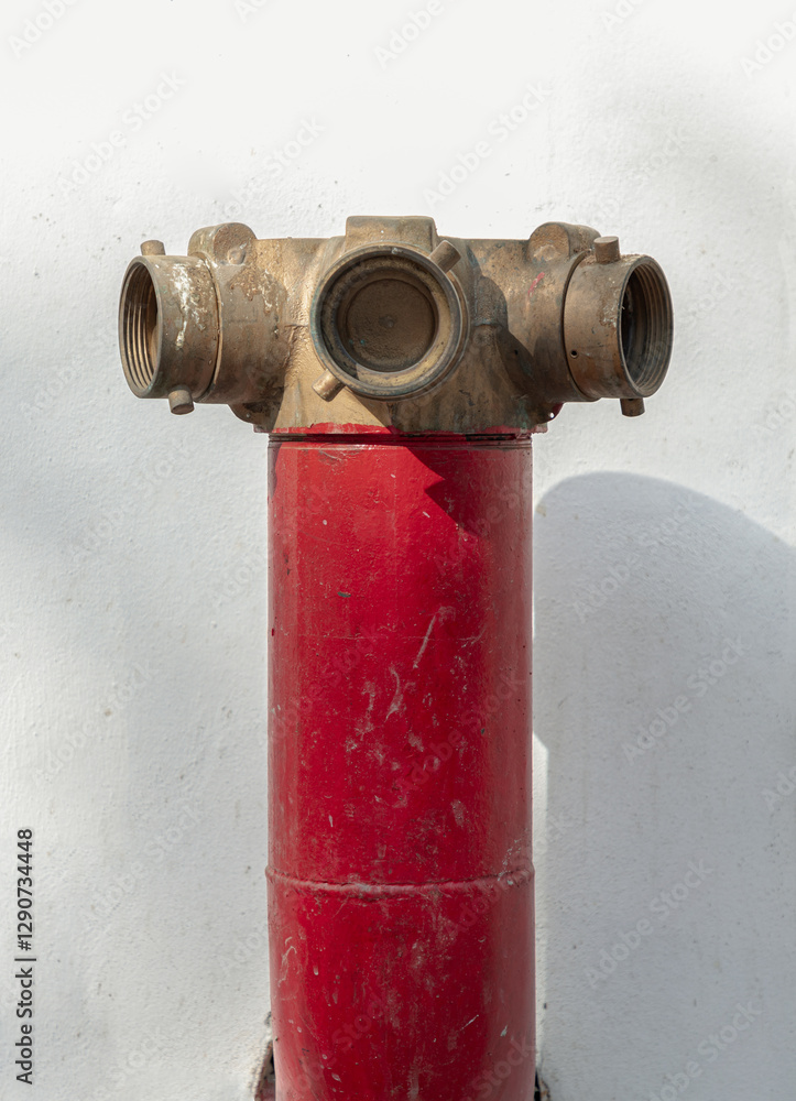 Red fire hydrant with Brass valve for Fire anticipation on land in front of an on white cement wall background. Fire Department Connections, Fire safety concept, use it as your Wallpaper, Poster.