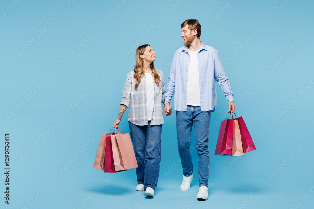 Full body young fun couple two friend family man woman wear shirt casual clothes together hold shopping paper package bags walk go isolated on plain blue background. Black Friday sale buy day concept Full body young fun couple two friend family man woman wear shirt casual clothes together hold shopping paper package bags walk go isolated on plain blue background. Black Friday sale buy day concept