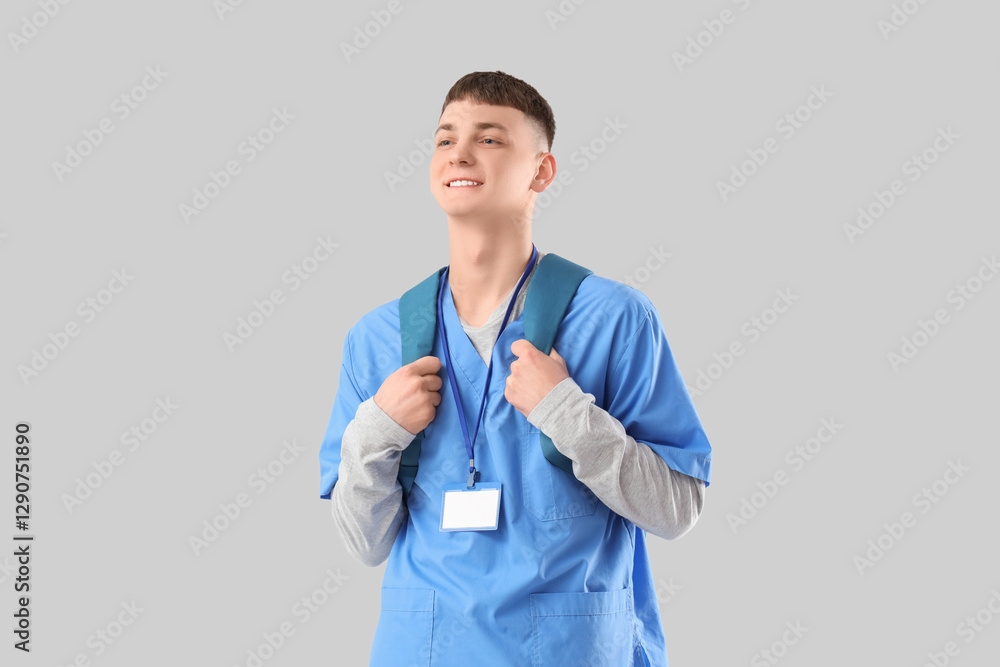 Male medical intern with backpack on light background
