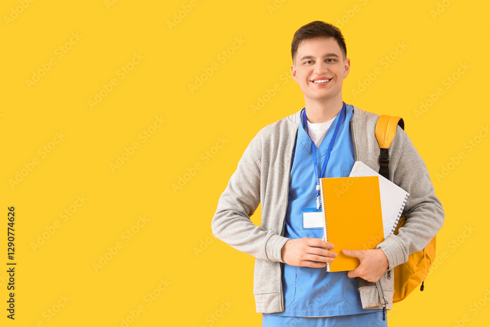 Male medical intern with backpack and notebooks on yellow background Male medical intern with backpack and notebooks on yellow background